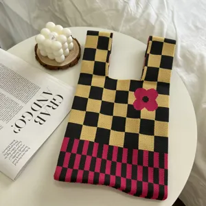 Knit tote bag with black and yellow checkerboard pattern, pink flower design and dual handles.