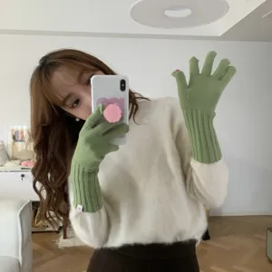 Closeup of green knit fingerless gloves with ribbed cuffs and cute brand label detail.