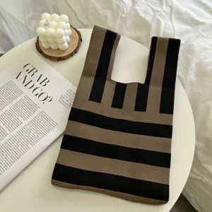 Knit handbag detail, brown and black striped tote bag displayed on a modern white table.