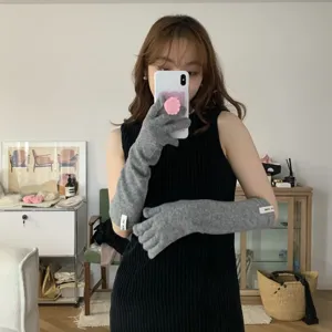 Vue détaillée de gants longs en tricot gris portés par un modèle, accessoire d'hiver.