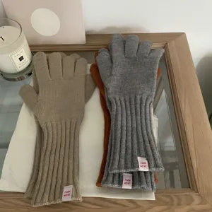 Detail view of solid color wool knit gloves featuring split fingers and cute pink brand labels.