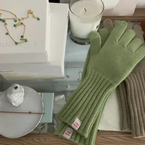 Detailed view of solid color knit gloves with cute pink label, cozy winter apparel piece.