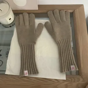 Detailed shot of solid color knit gloves with cuff tags, showcasing soft texture and cozy warmth.