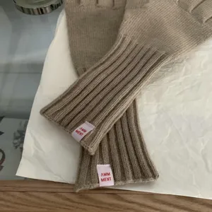 Close-up detail of cozy knit gloves in solid khaki color, showing the ribbed cuff texture and label.