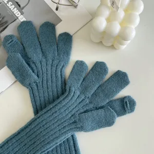 Close-up detail of women winter warm thick blue knit long wrist gloves, soft ribbed texture.