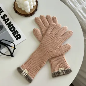 Primer plano de elegantes guantes de punto con puños acanalados en una mesa blanca limpia.