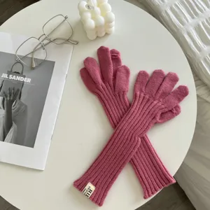 Close-up detail of soft pink ribbed knit long gloves, showcasing cozy texture and cuff tag.