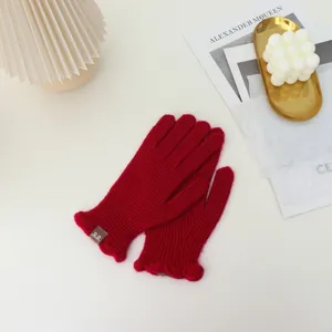 Detail view of red knit winter gloves with cute ruffle trim, warm split finger design.