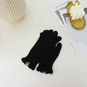 Cozy black knit winter gloves featuring cute ruffled cuffs and chic leather brand labels for daily warmth.