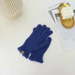 Close-up detail of blue knitted touchscreen gloves featuring a small decorative label.
