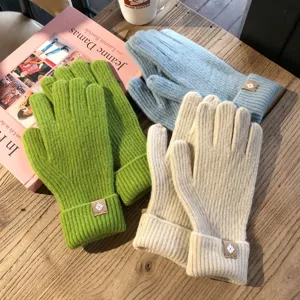 Detailansicht von einfarbigen Wollstrick-Handschuhen mit Touchscreen-Funktion und modischem Patch.