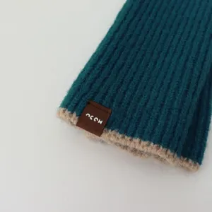 Knit fingerless glove detail shot, dark green ribbed fabric with contrast beige trim.