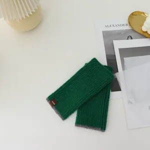 Detail shot of winter fingerless knit gloves in green with grey color block trim. Cozy wool.