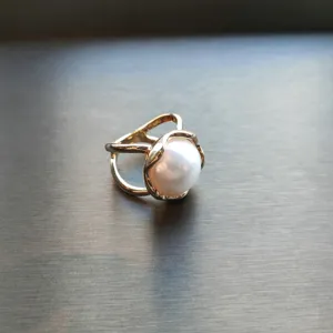 Detailed close-up shot of a golden wavy pearl ring and chic scarf buckle jewelry item