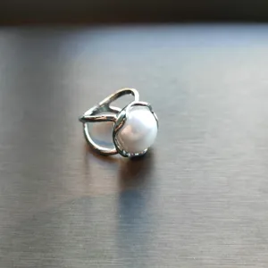 Close-up detail of silver metal ring and scarf buckle featuring a classic white pearl.