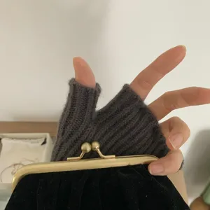Close-up detail of dark gray knitted fingerless gloves showing warm ribbed texture.
