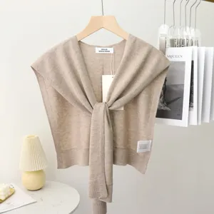 Detailaufnahme des beigen Strick-Schal-Capes, elegantes Vorn-Bind-Design, weicher Stoff.