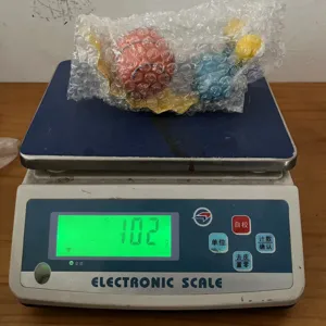 Compact item wrapped in bubble wrap shown on an electronic weighing scale for details.