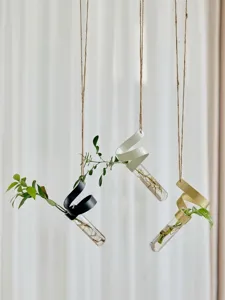 Detailed shot of hanging hydroponic glass test tube vase with metal spiral bracket, plant decor.