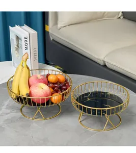 Detail shot of luxury gold metal fruit basket with black marble base for stylish home decor.