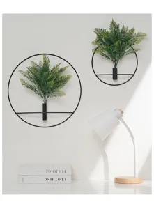 Detail view of modern black metal round wall hanging planter with artificial fern leaves.