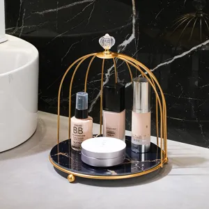 Gold metal birdcage cosmetic organizer with marble base for desktop makeup and skincare storage.