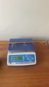Vista dettagliata del gancio da parete in metallo dorato mostrato su una bilancia digitale.