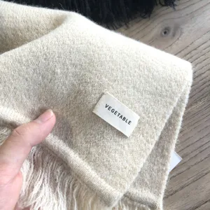Beige Strickschal Detailansicht zeigt weiche Wintertextur und gewebtes Etikett.