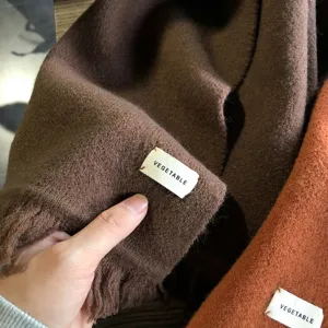 Nahaufnahme der weichen Winterschal Textur und des dekorativen Markenetikett-Designs.
