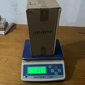 Cardboard packaging box detail showing size 14x14x27cm and weight on digital scale.
