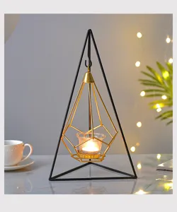 Close-up detail shot of Nordic geometric metal candle holder with glass cup and warm candlelight.