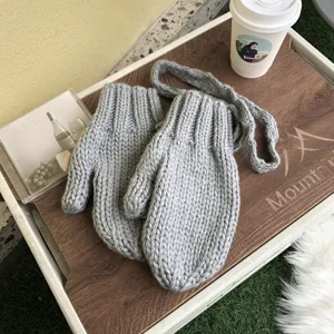 Grey thick knit winter mittens with hanging string, cozy wool gloves for cold weather detail view.