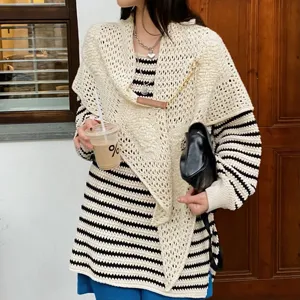 Detailed shot of the striped knitted top featuring a crochet shawl cape with leather chain buckle.
