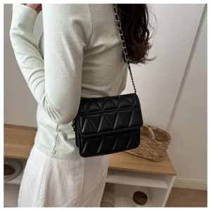 Detail view of black quilted chain shoulder bag, showing triangular texture and metallic strap.