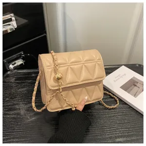 Detail shot of the beige quilted crossbody bag featuring a stylish metal chain and chic design.