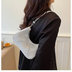 Vue détaillée du sac porté épaule croissant élégant, orné d'un joli nœud et d'un charm suspendu.