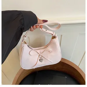 Gros plan sur le sac hobo rose sous les aisselles avec un beau nœud et un pendentif cœur.