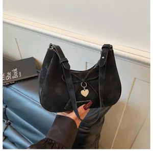 Vue rapprochée détaillée du sac porté épaule noir en suédine avec nœud mignon et charm cœur.