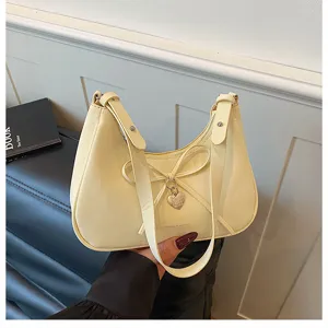 Sac bandoulière hobo jaune clair avec nœud et pendentif cœur pour femme, design chic et tendance.
