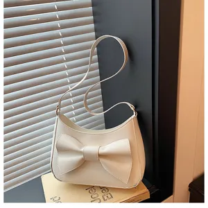 Detailed close-up view of the elegant white shoulder bag with chic bow on dark surface.