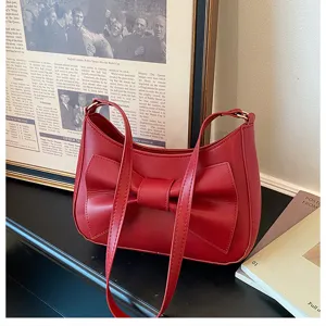 Red shoulder bag detail shot featuring a chic bow design and sleek strap for women.