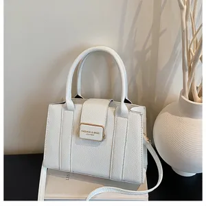 Vue détaillée du sac à main blanc en cuir PU avec fermoir métallique sur table sombre.