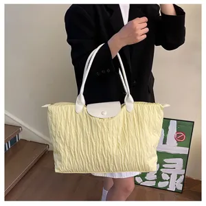 Detailed view of the yellow pleated tote bag with white leather handles and elegant flap.