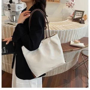 Detailed close-up of white canvas tote bag with brown straps for women daily commuting.