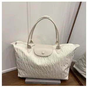 Detail shot of the cream pleated travel shoulder bag featuring a leather flap and top zipper.