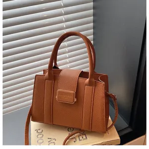 Détail du sac à main en cuir PU marron avec fermoir métallique frontal, double poignée et texture.