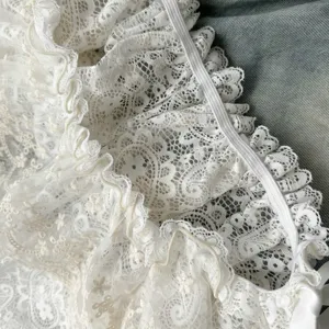 White double-layer lace skirt detail, hollow-out embroidery mini skirt extension and layered trim.