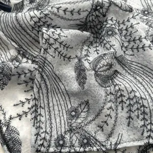 White fabric with intricate black floral embroidery detail for elegant French layered skirt.