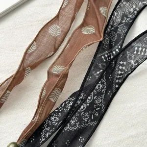 Close-up detail of vintage patterned silk ribbon scarf, elegant neck accessory for women.