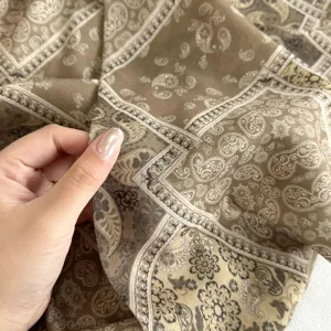 Nahaufnahme des braunen Paisley-Stoffes mit feinem geometrischem Muster und weicher Textur.
